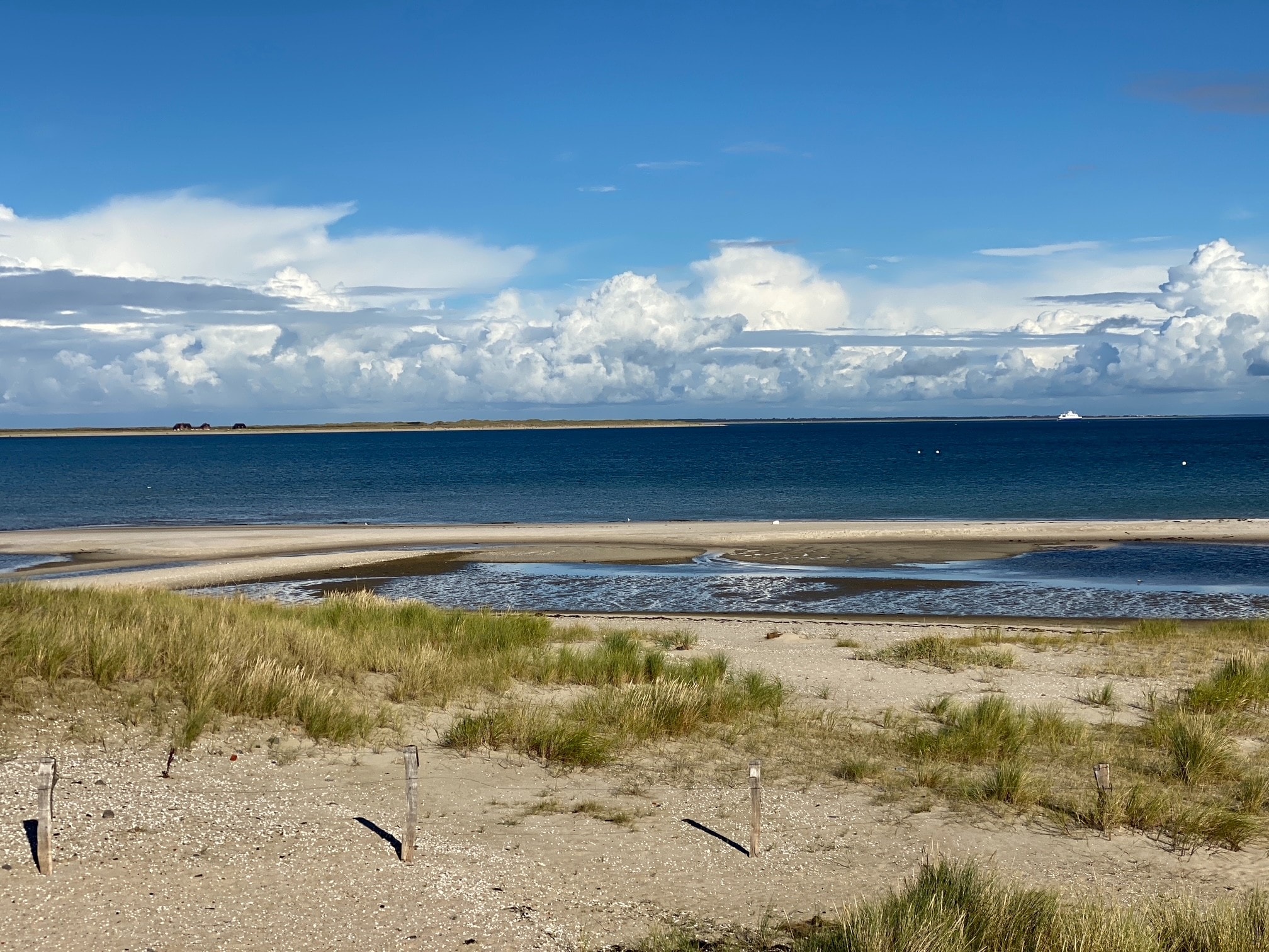 Heller Sylter Strand mit Dünengras, blauem Meer und weiten Schönwetterwolken